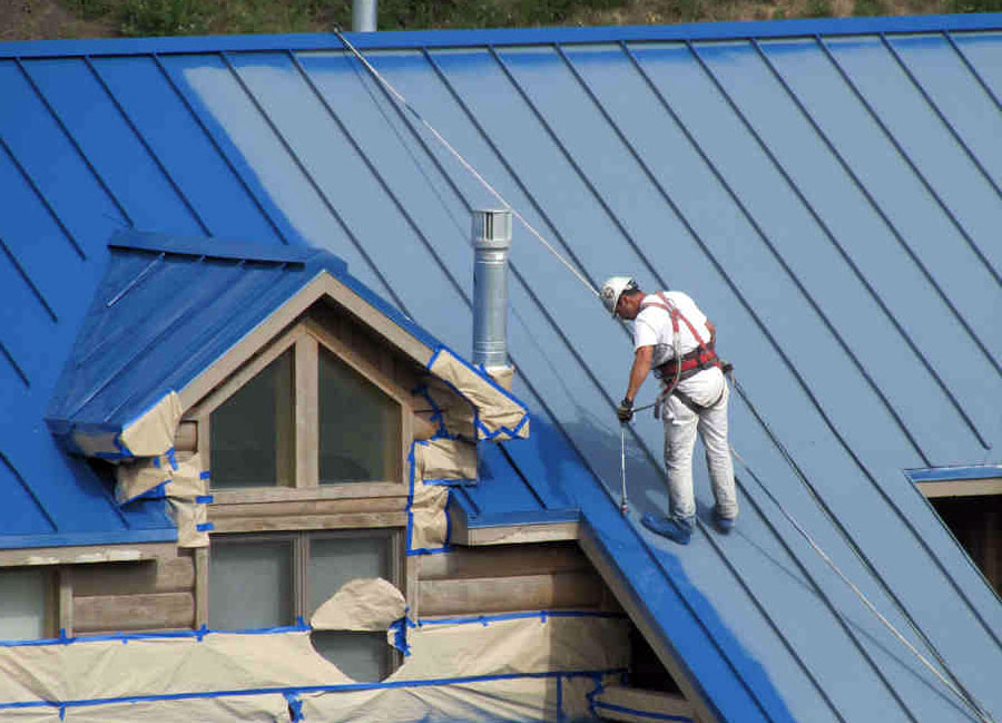 a worker painting metal roofing